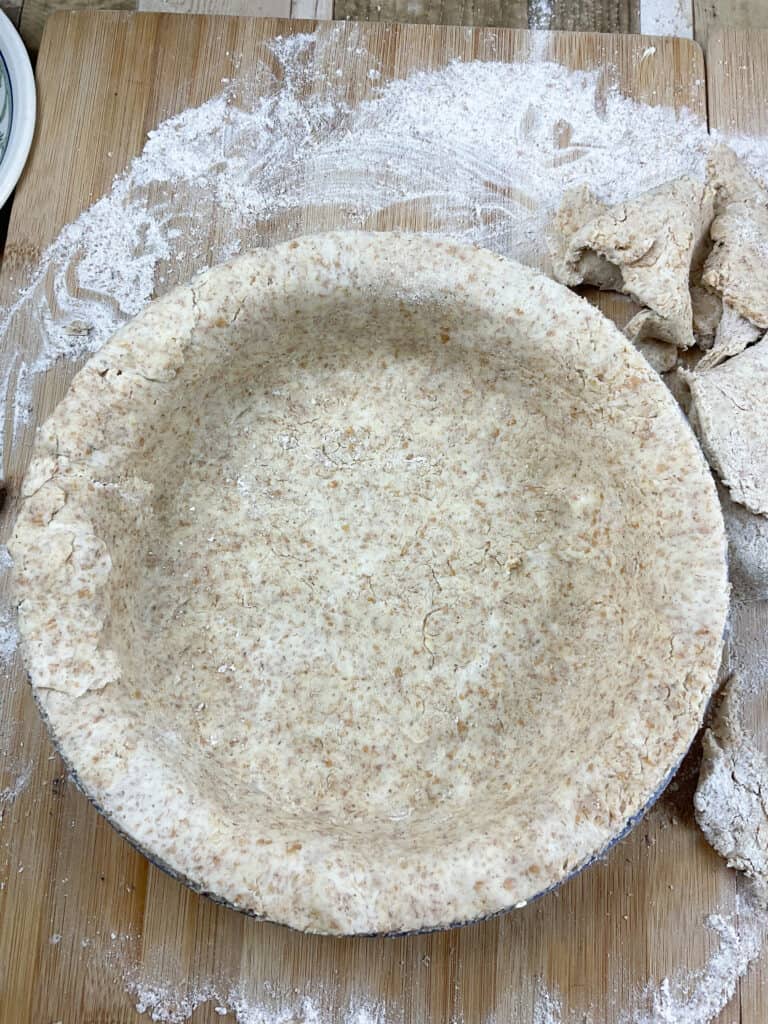 Unbaked pastry case in pie dish on a floured board.