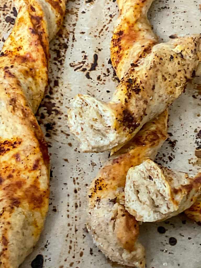 close up of baked breadsticks on baking tray with one halved to show the inside texture.