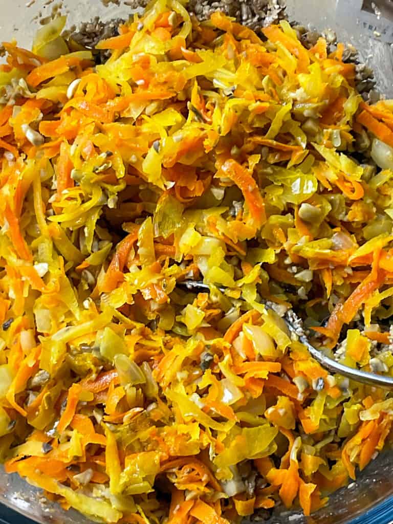 cooked veggies added to spices and haggis ingredients in mixing bowl and stirred with silver spoon.