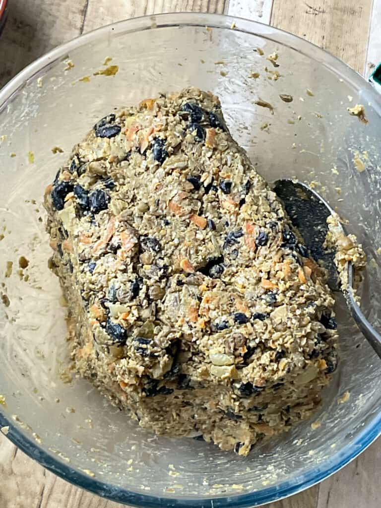 vegan haggis mixture being pressed together with a silver spoon to form an oval shape.