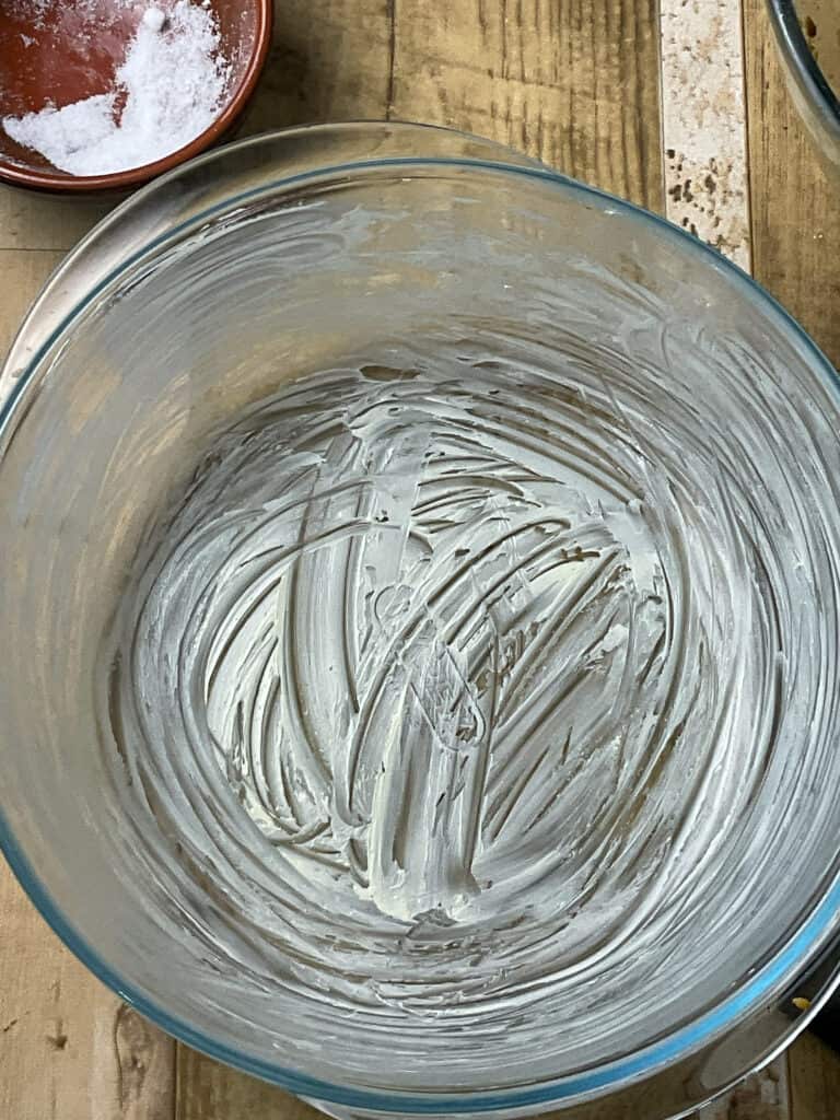 casserole dish greased with margarine, small salt dish to side, and wooden table background.