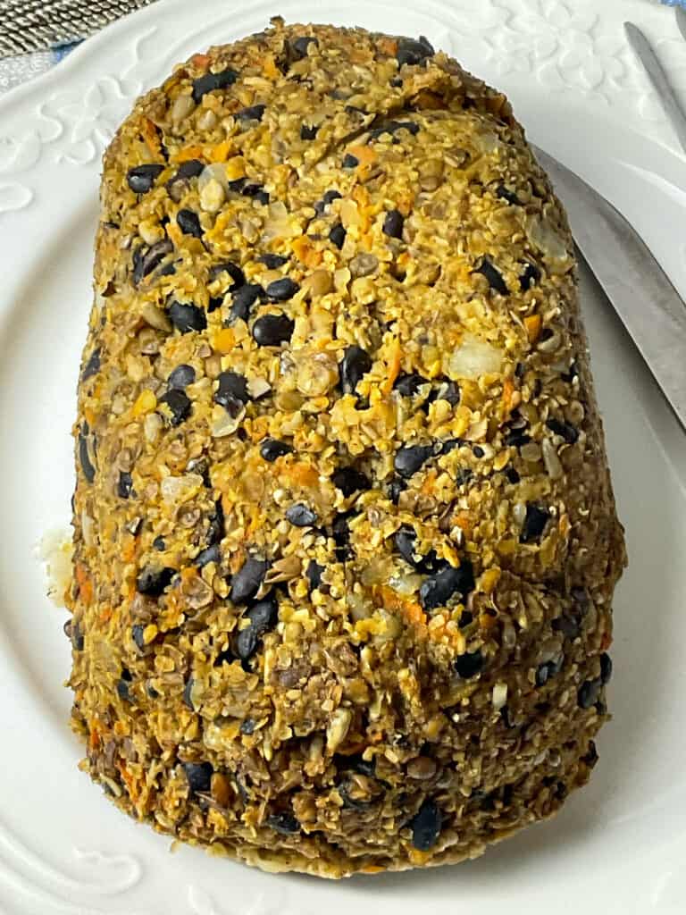 vegan haggis cooked and sitting on a white serving plate ready to serve.