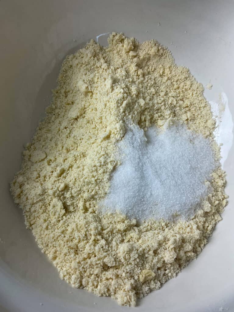 Sugar added to crumbed flour and margarine mixture in mixing bowl.