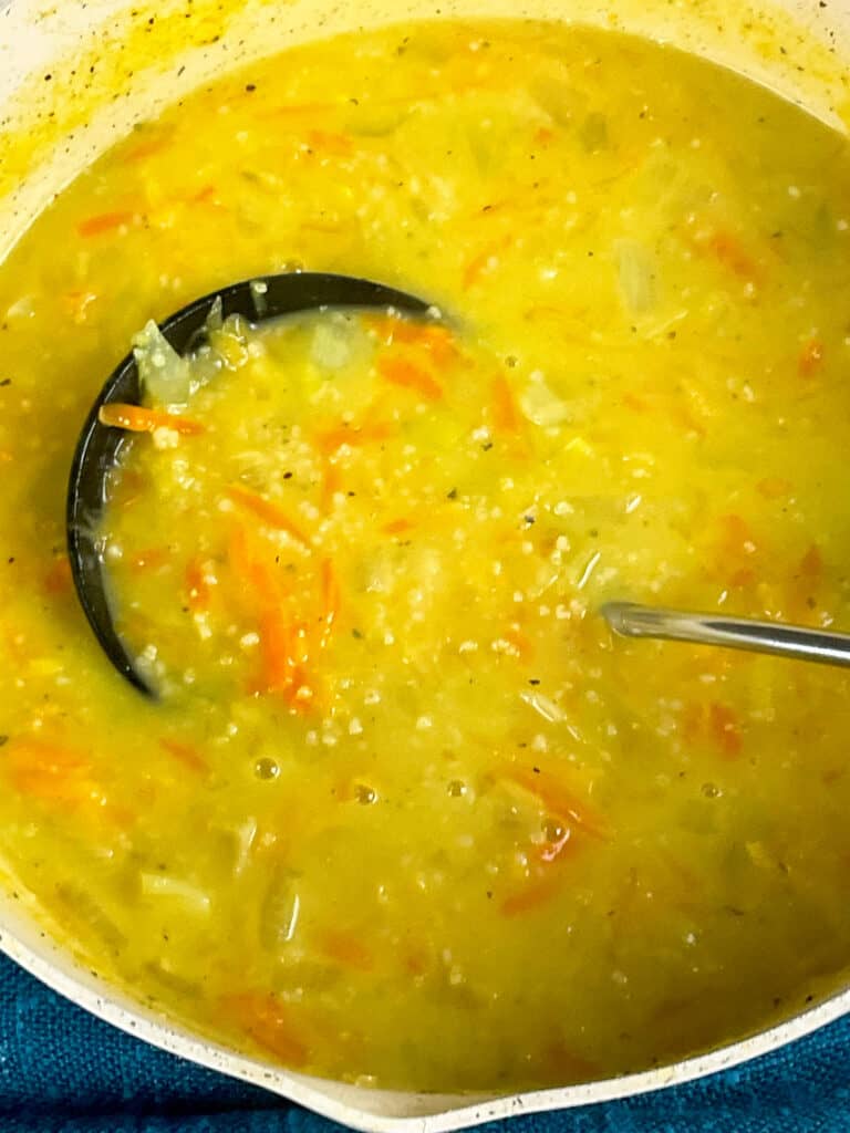 Orcadian oatmeal soup with milk stirred through and soup ladle in pot ready to serve.