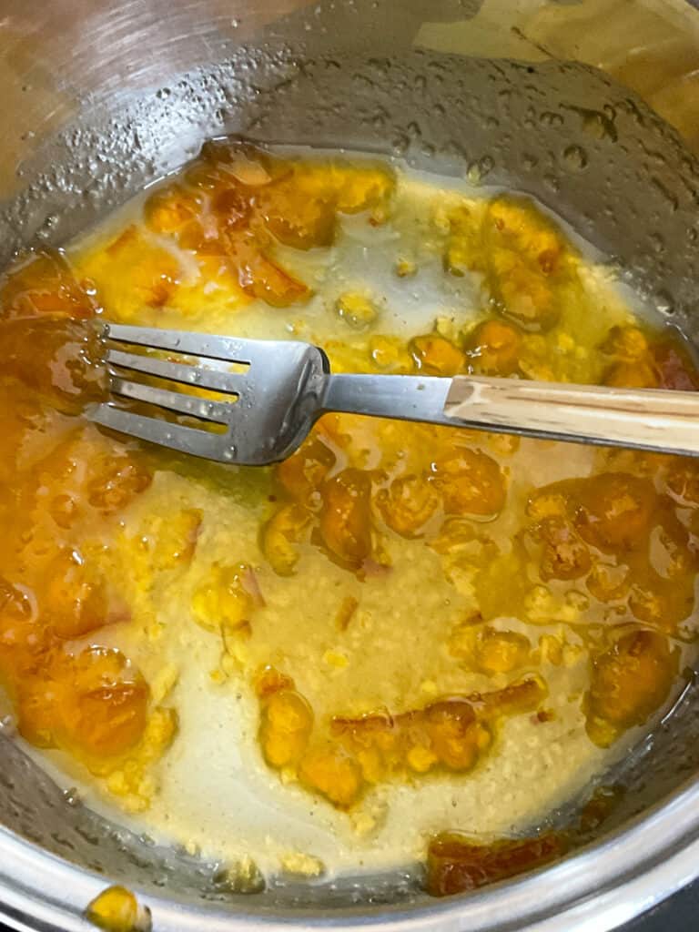 marmalade and water added to small saucepan with a fork stirring together.