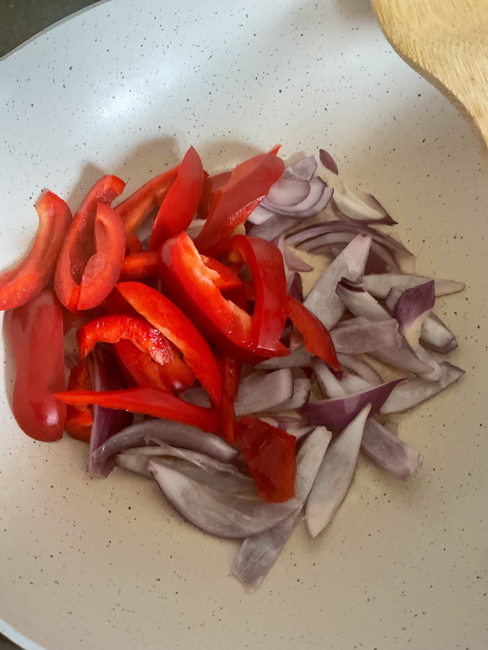 Sliced peppers and onions in pan.