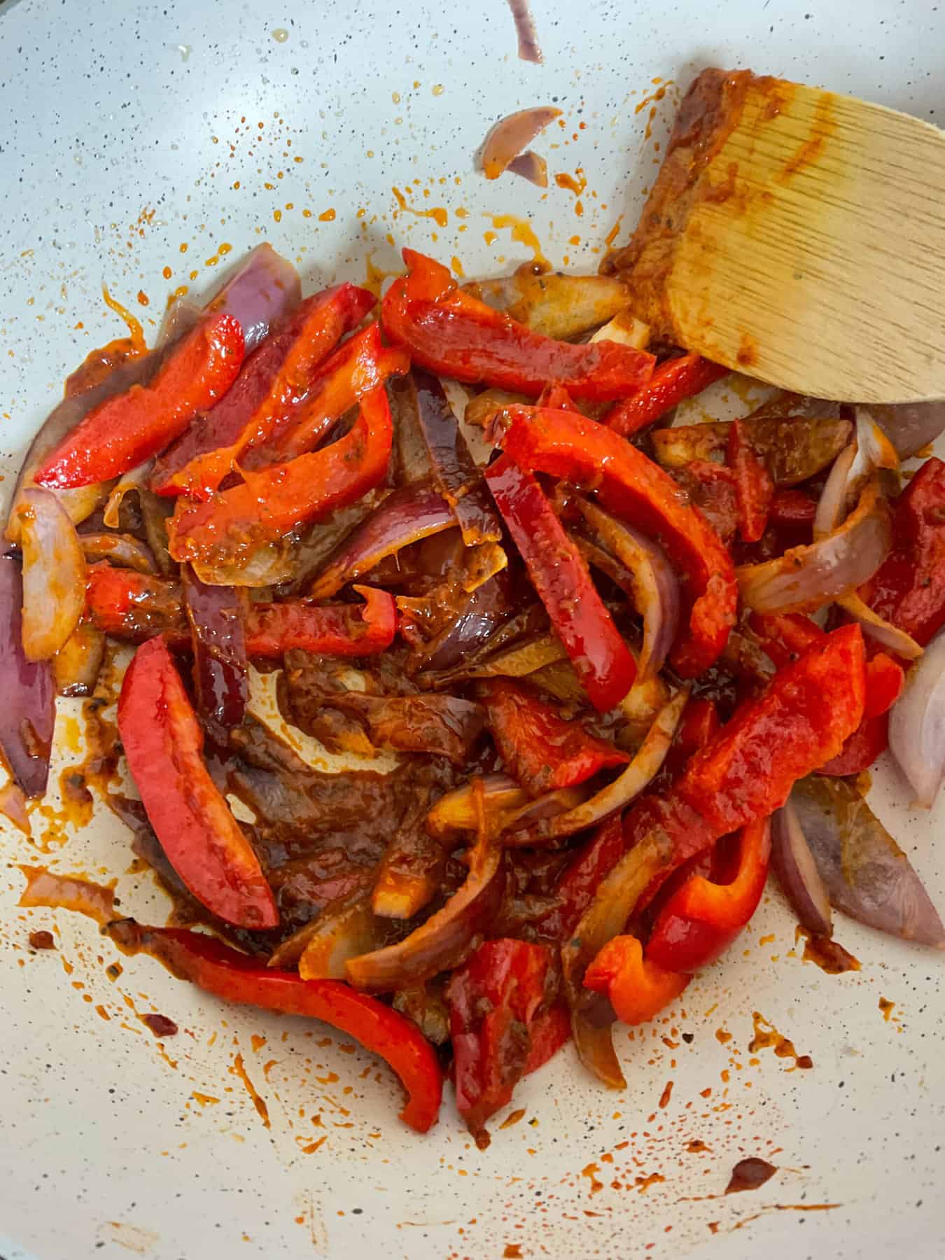 Thai curry paste stirred through veggies in pan.