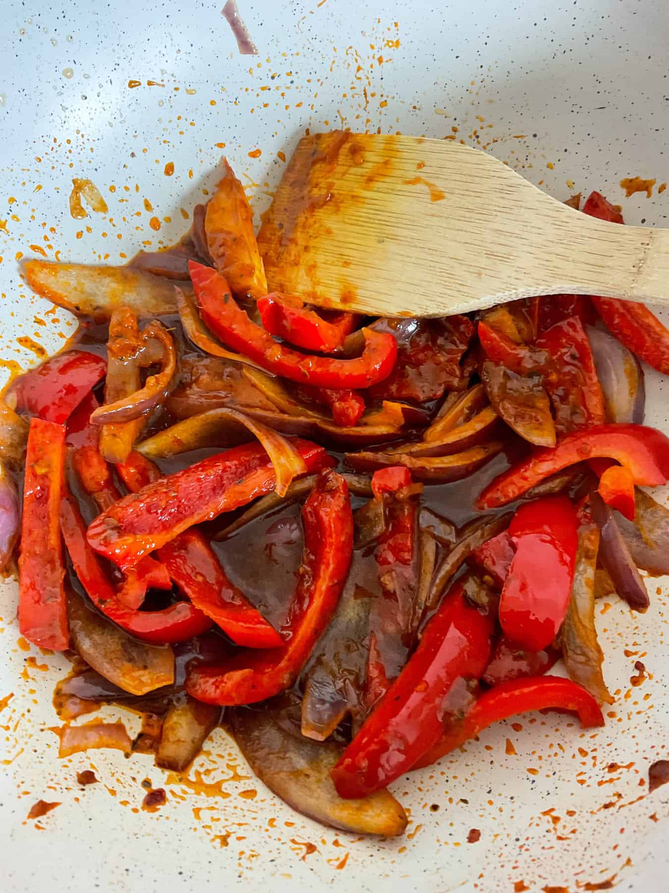 veggies cooking in pan with wooden spatula.