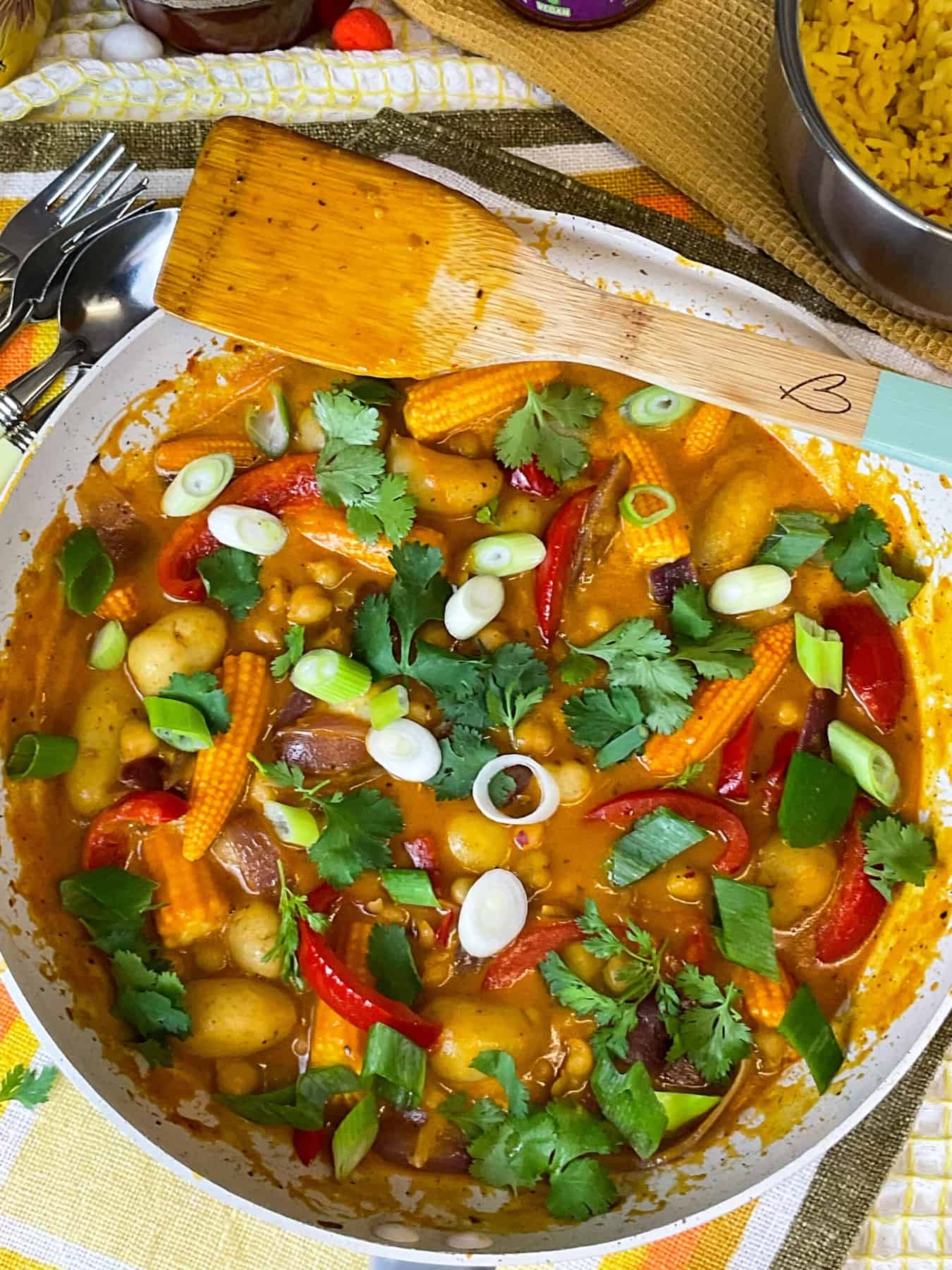 A close up of a pan with curry, spatula to the side and a pot of rice, featured image.