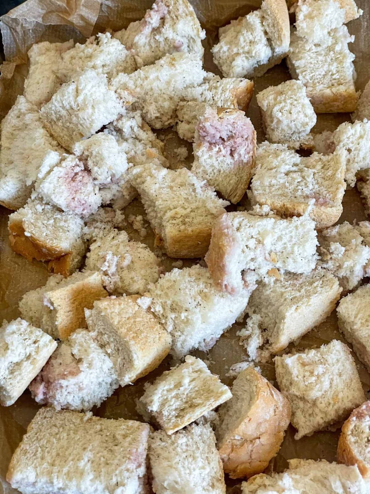 Crusty bread ripped into chunks and tossed in red wine vinegar, and spread out on a baking tray.