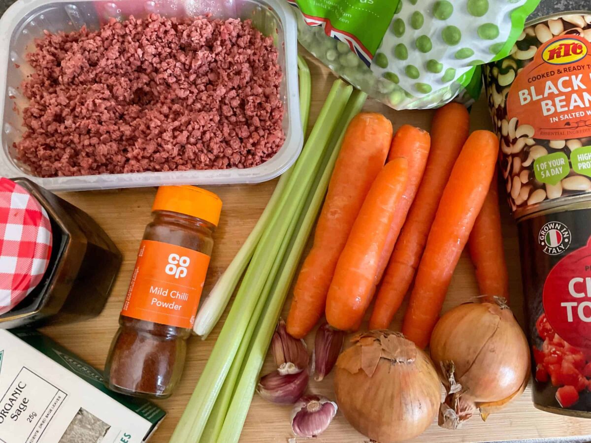 Ingredients for vegan chuck wagon stew laid out on a wooden chopping board.