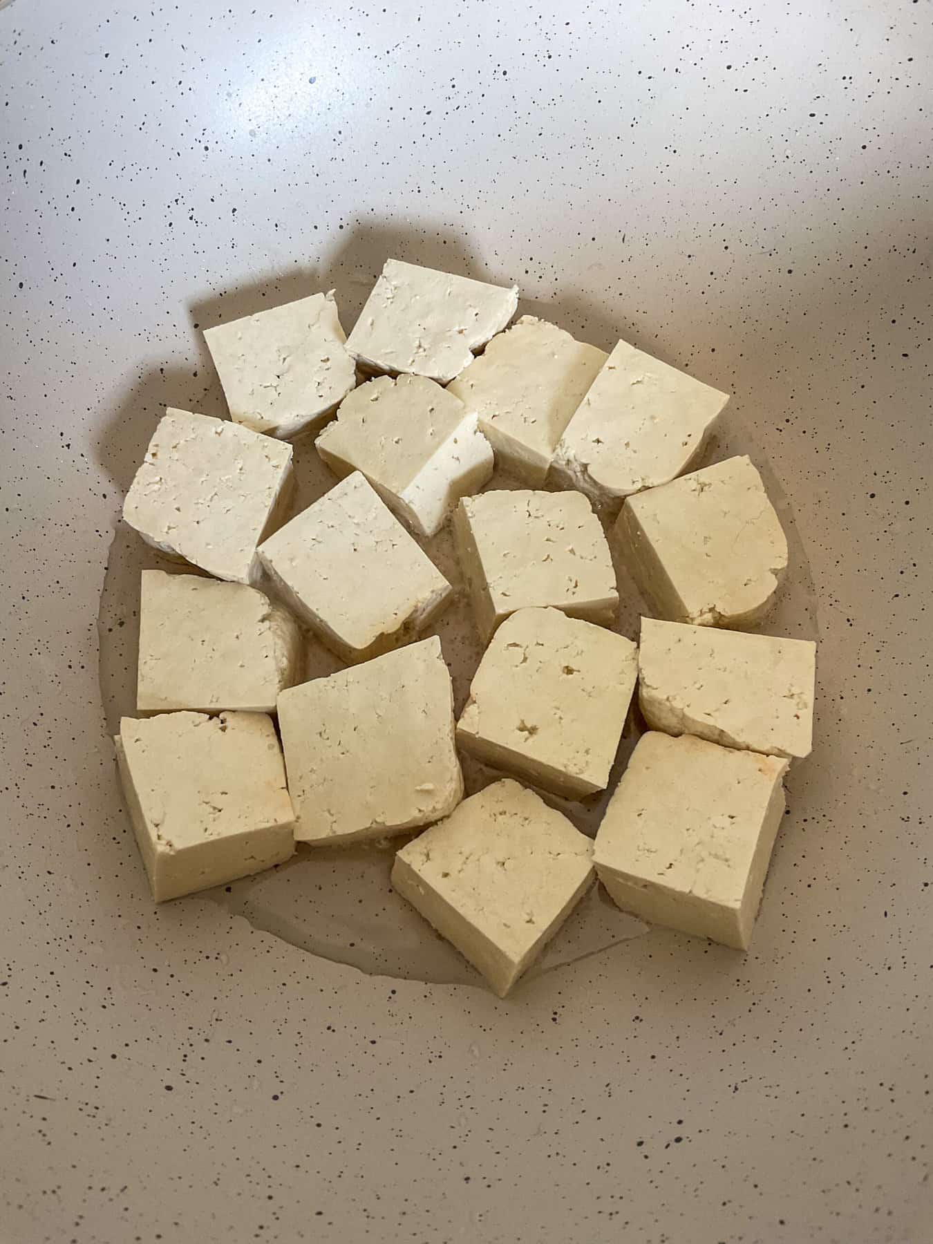 Cubes of tofu cooking in coconut oil in wok.