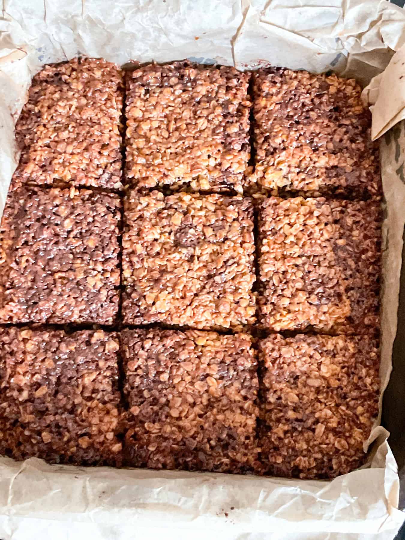 Baked chocolate flapjacks marked into squares in baking tin,