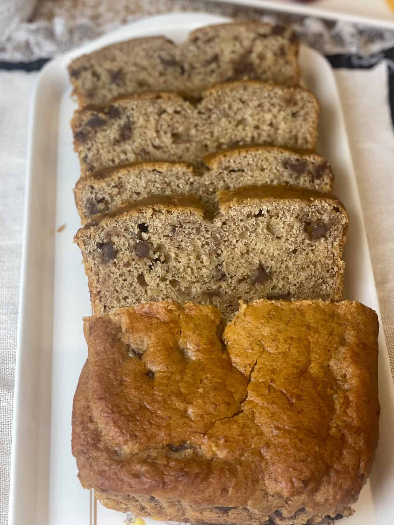 A tray of banana bread slices with whole chunk of bread at front.