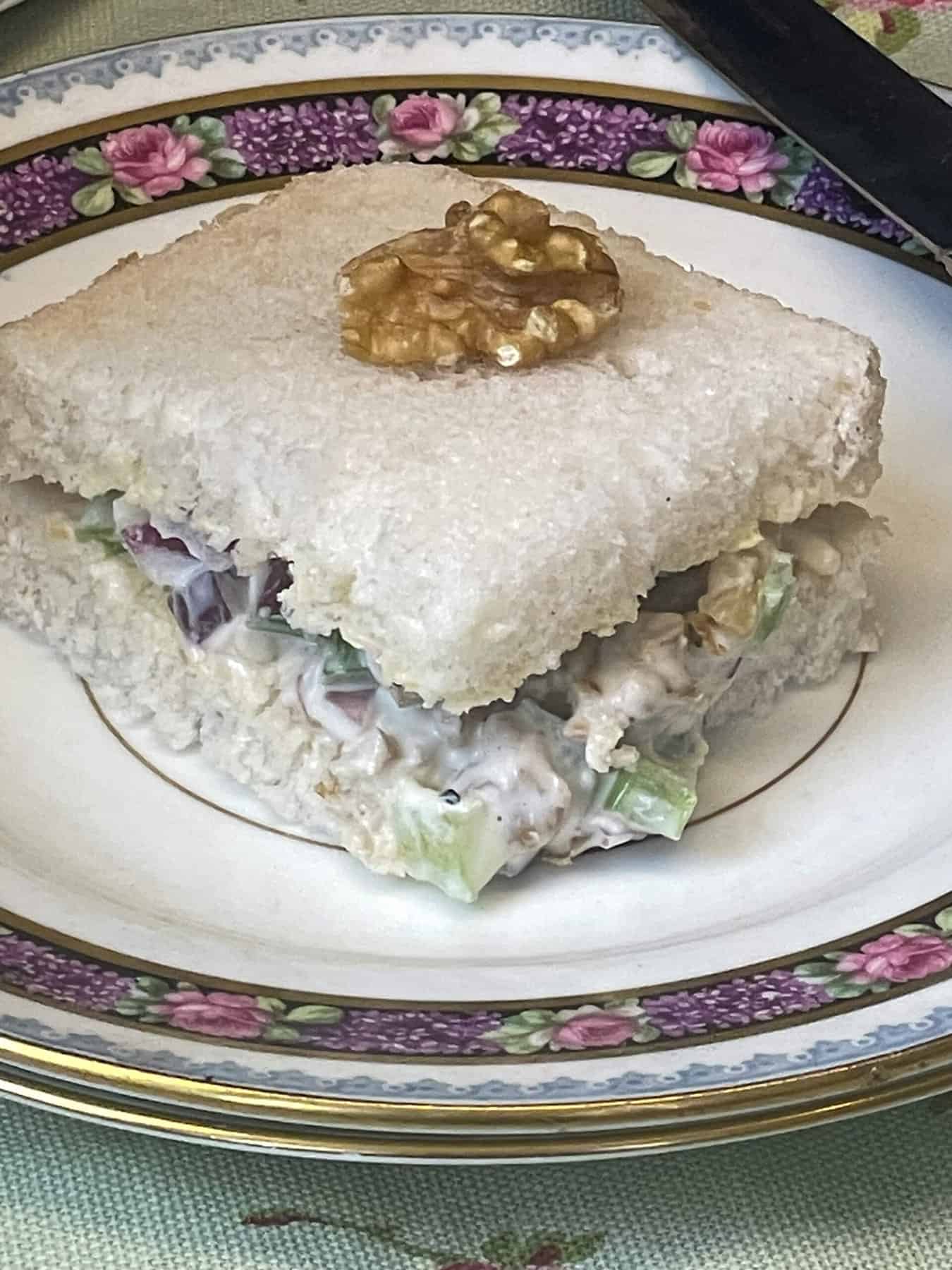 A dainty small sandwich on purple patterned rimmed vintage plate.