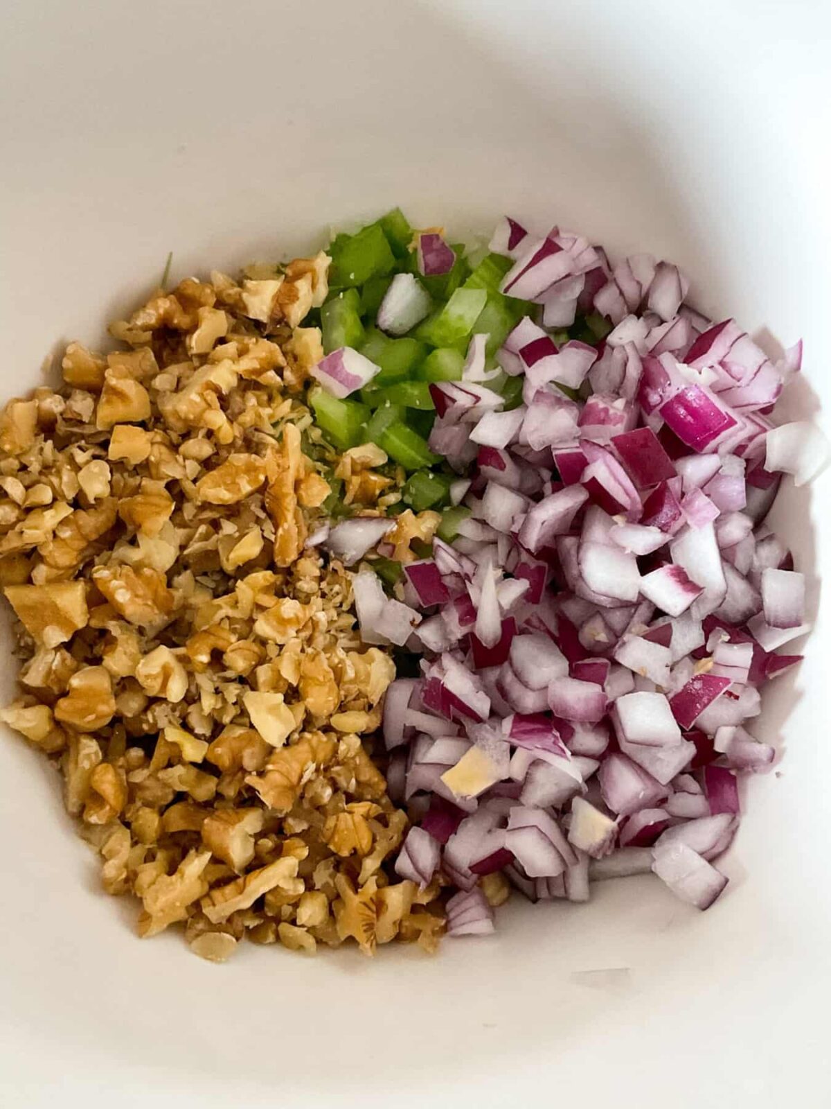 Fine diced red onion with the diced celery and also diced walnut in the mixing bowl.