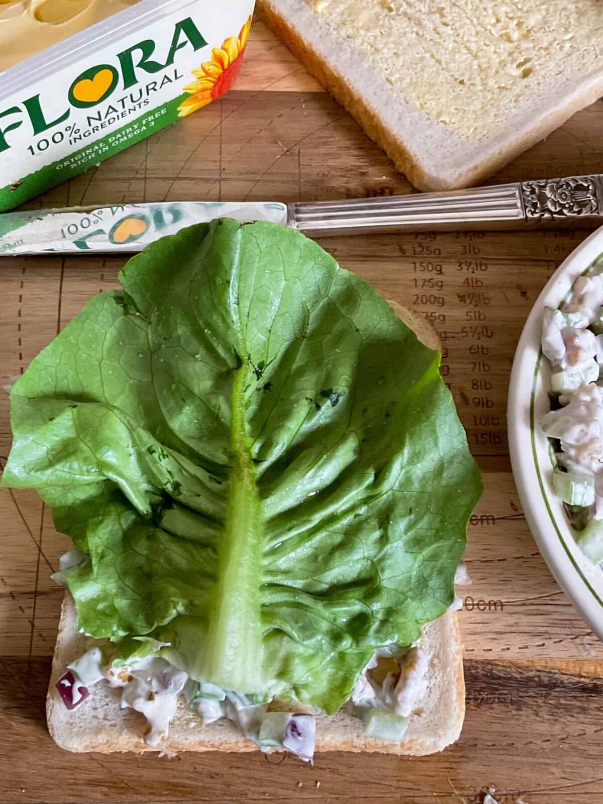 Preparing walnut celery sandwiches, lettuce leaf on sandwich on wooden board.