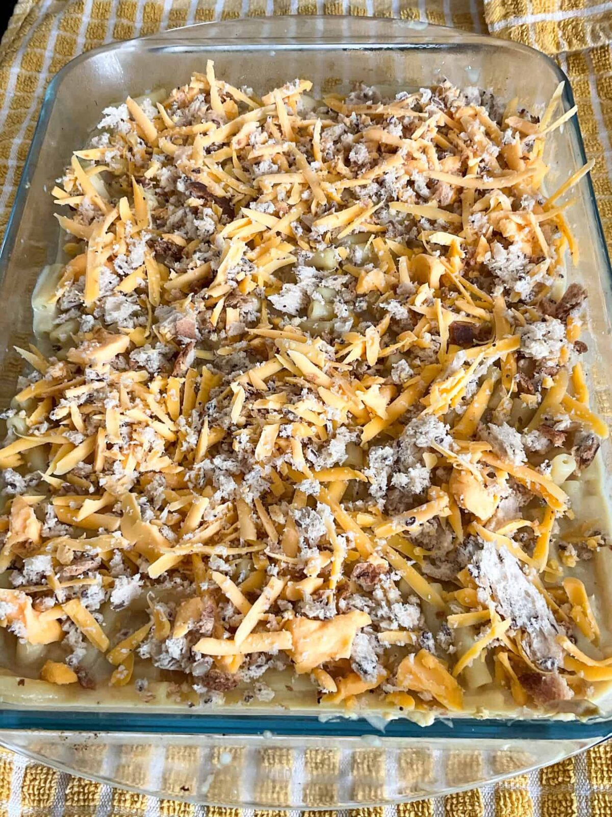 Macaroni cheese and breadcrumb topping added to macaroni cheese in the baking dish.