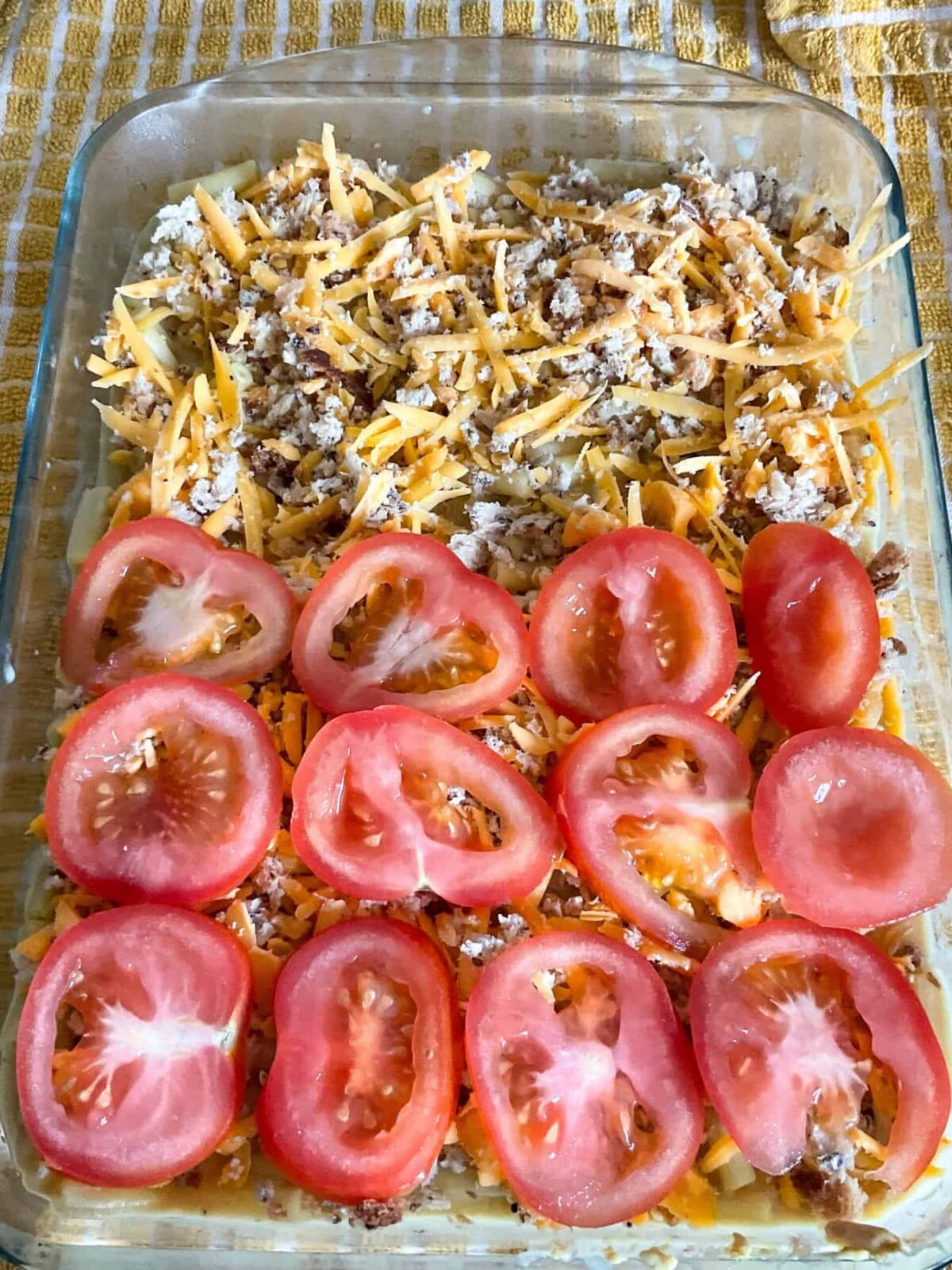 Sliced tomatoes added to stove-top macaroni cheese in baking dish.