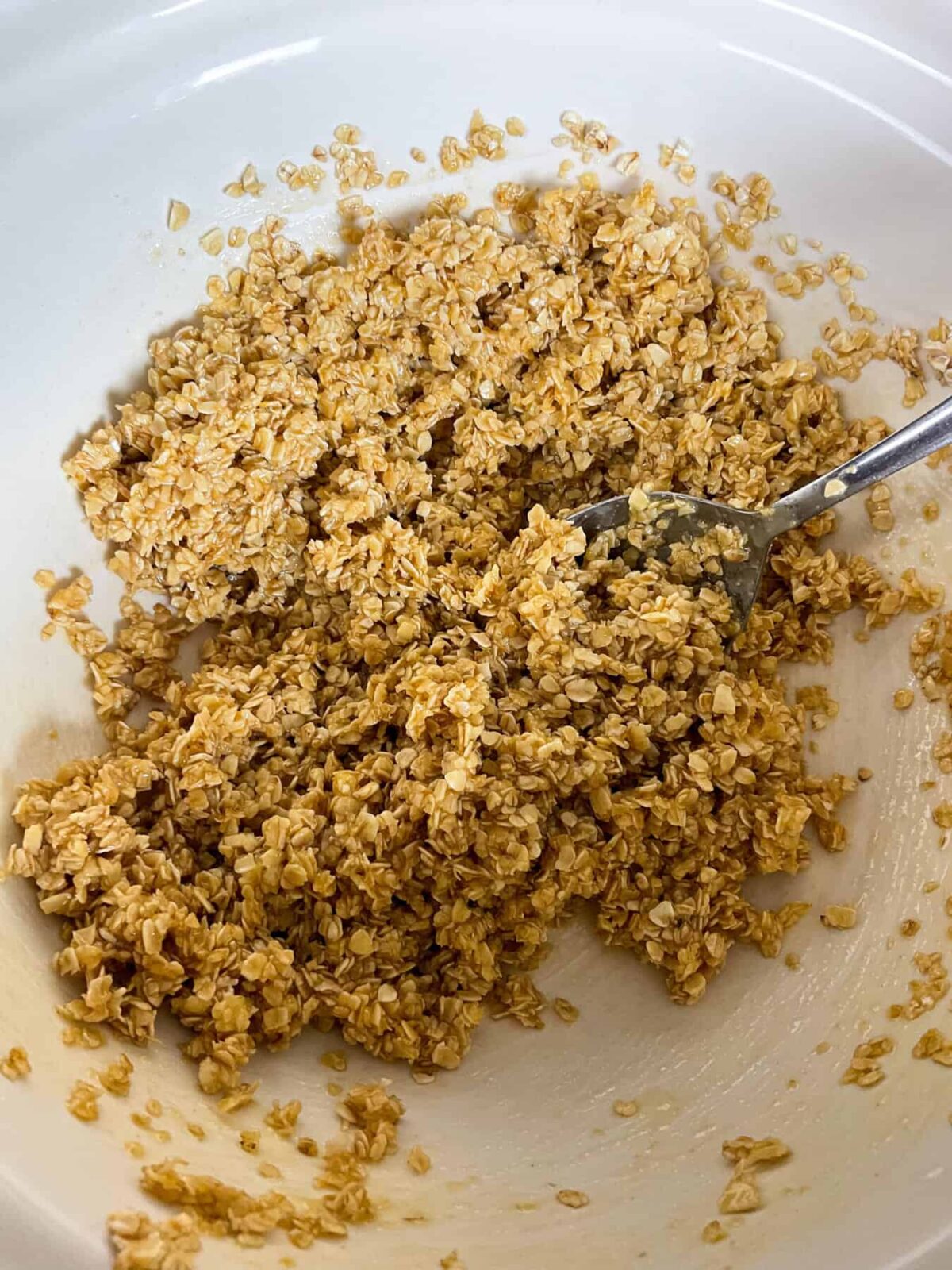 Flapjack ingredients mixed together in mixing bowl with spoon.