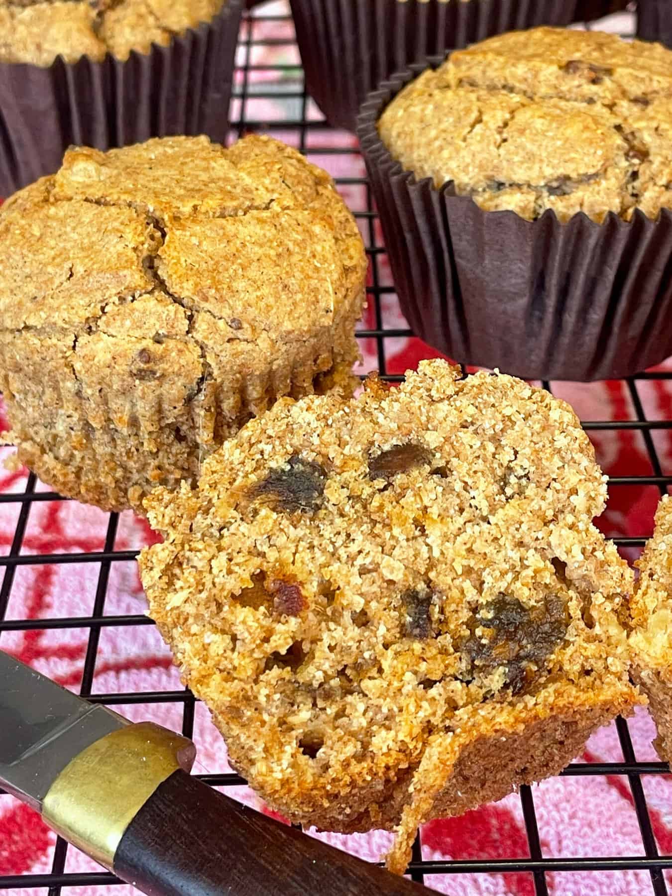 Bran muffins on wire cooling rack with brown handled knife.