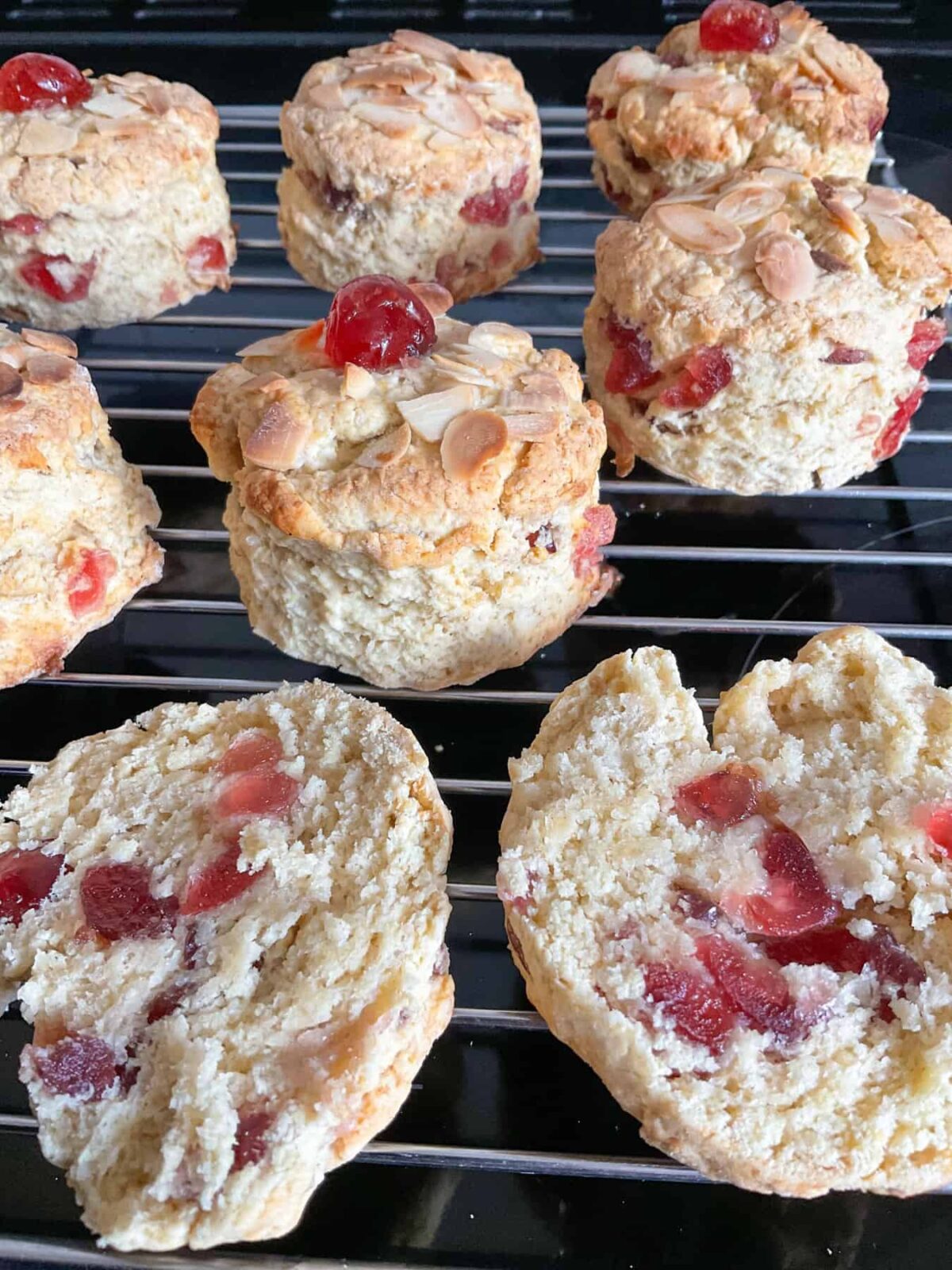 A batch of cherry Bakewell scones on a wire rack just out of the oven.