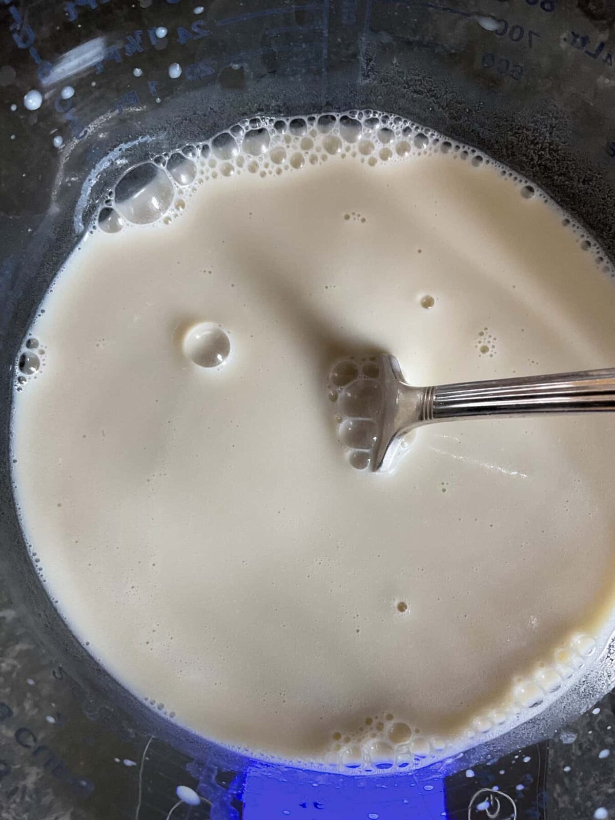 Milk mixed with vinegar to create a vegan buttermilk in a glass jug with cutlery fork.