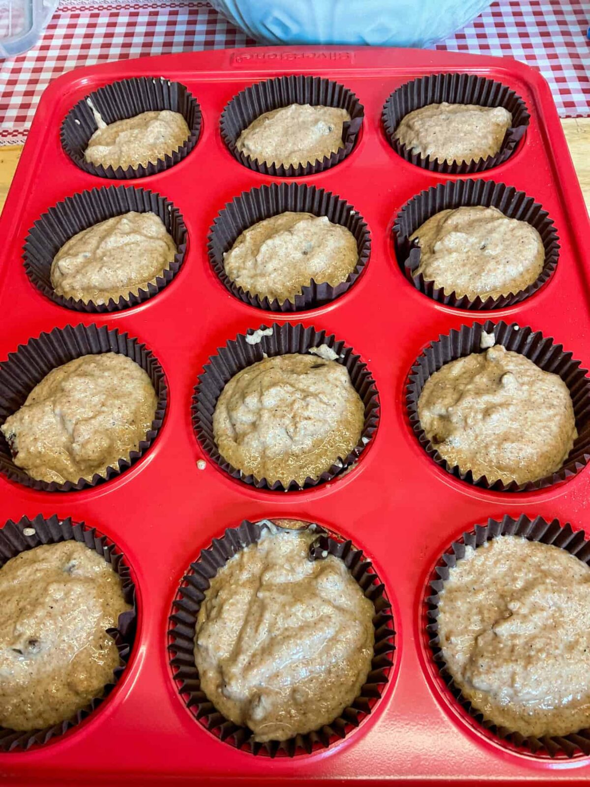 Unbaked muffin mixture divided between 12 muffin cups on baking tray.