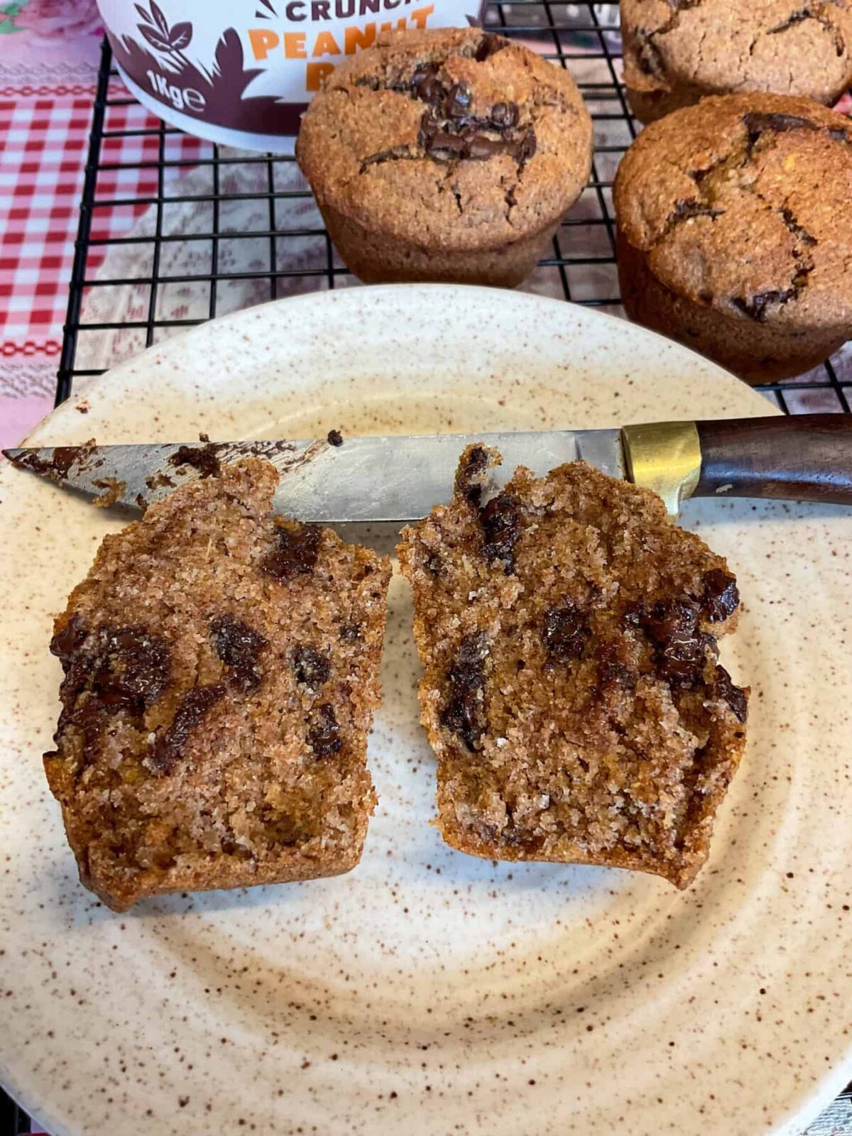 Choc chip bran muffin sliced in two on a light brown speckled plate.