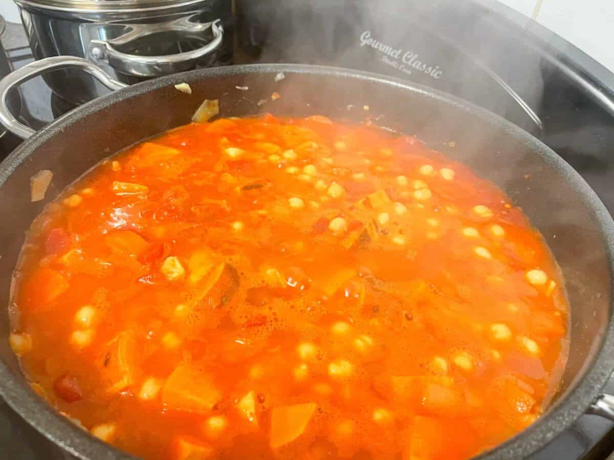 Chickpeas and canned tomatoes added to pan.