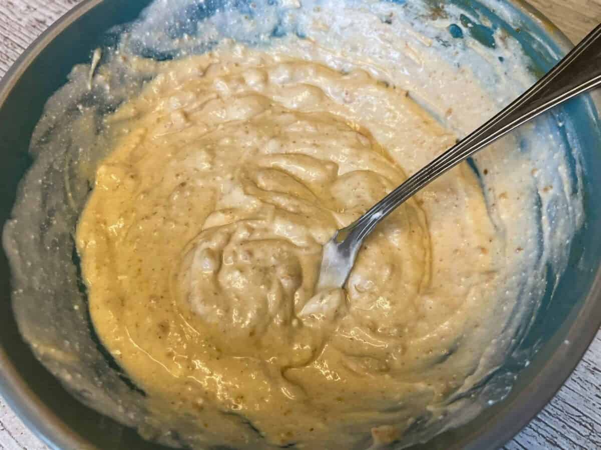 Peanut butter and coconut milk mixed together in small bowl with spoon.
