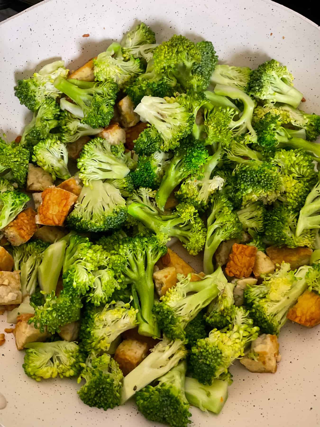 Broccoli and tempeh stir-frying in pan.