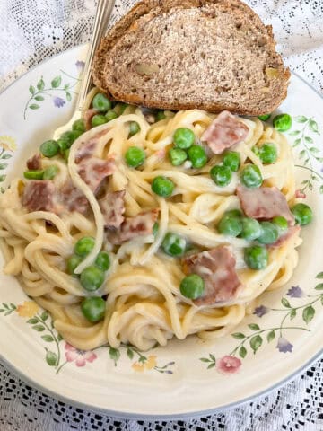 Vegan Spaghetti Carbonara served on plate with bread.