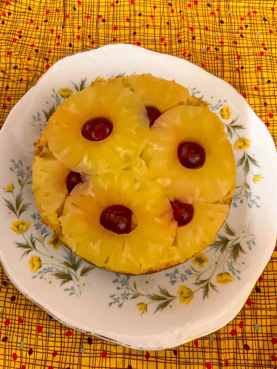 Photo of vegan pineapple upside-down pudding on a serving plate with yellow patterned background.