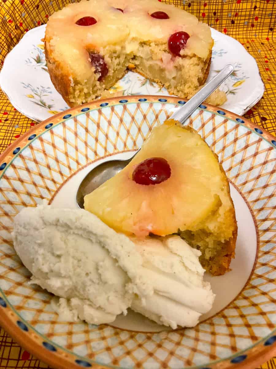 Slice of upside down pudding with scoop of ice cream and pudding in background.