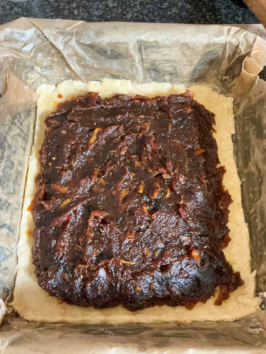 Unbaked date slice with filling added to pastry.