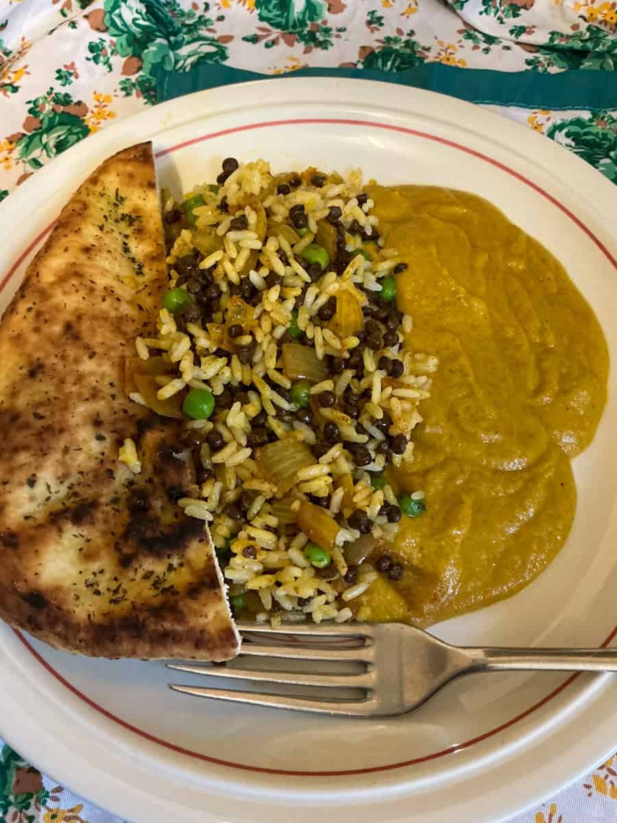 Vegan biriani served with curry sauce and naan bread.