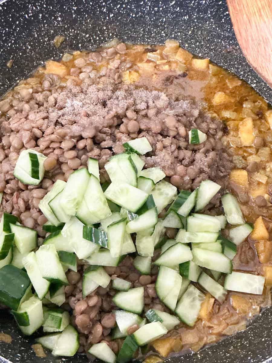 cooked lentils and cucumber added to frying pan with cooked ingredients