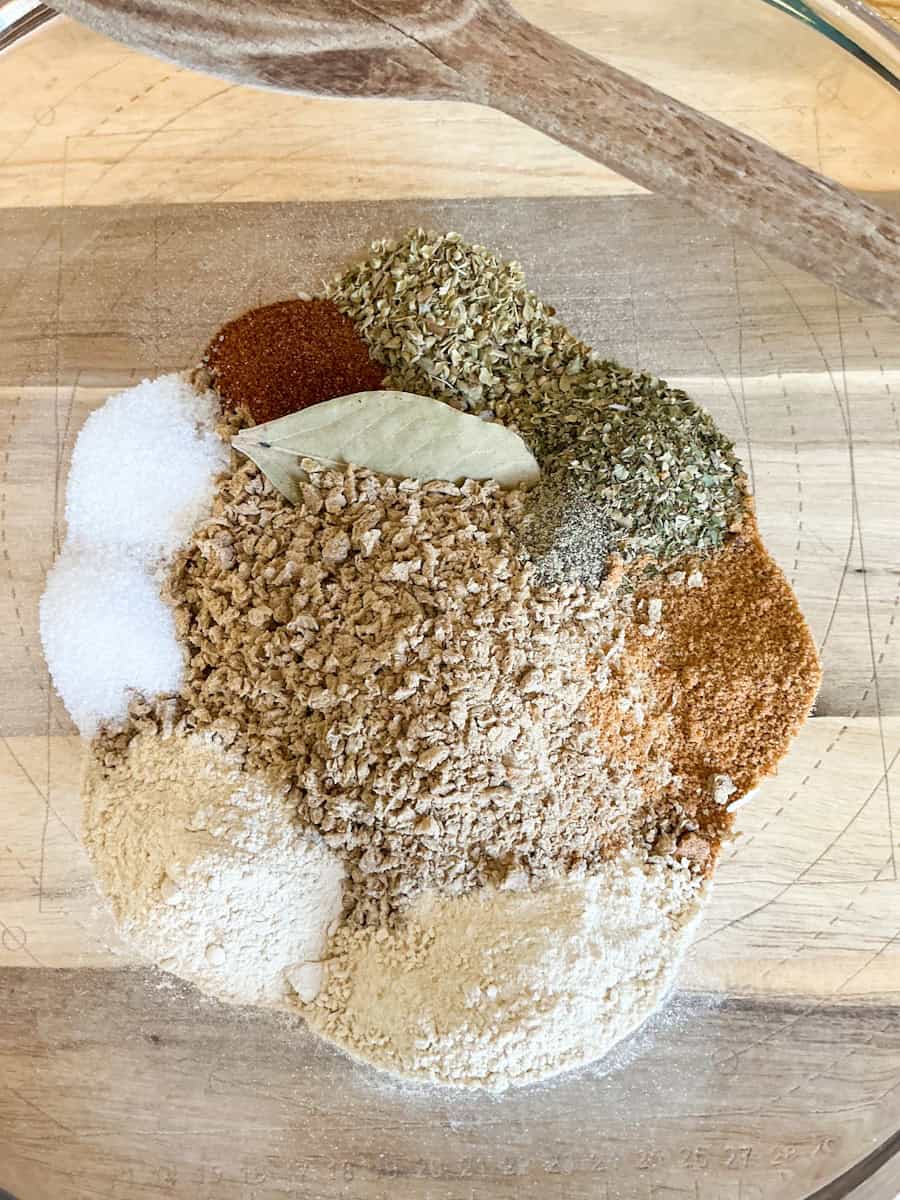Dried ingredients for Beanfeast Bolognese added to mixing bowl on a wooden chopping board.