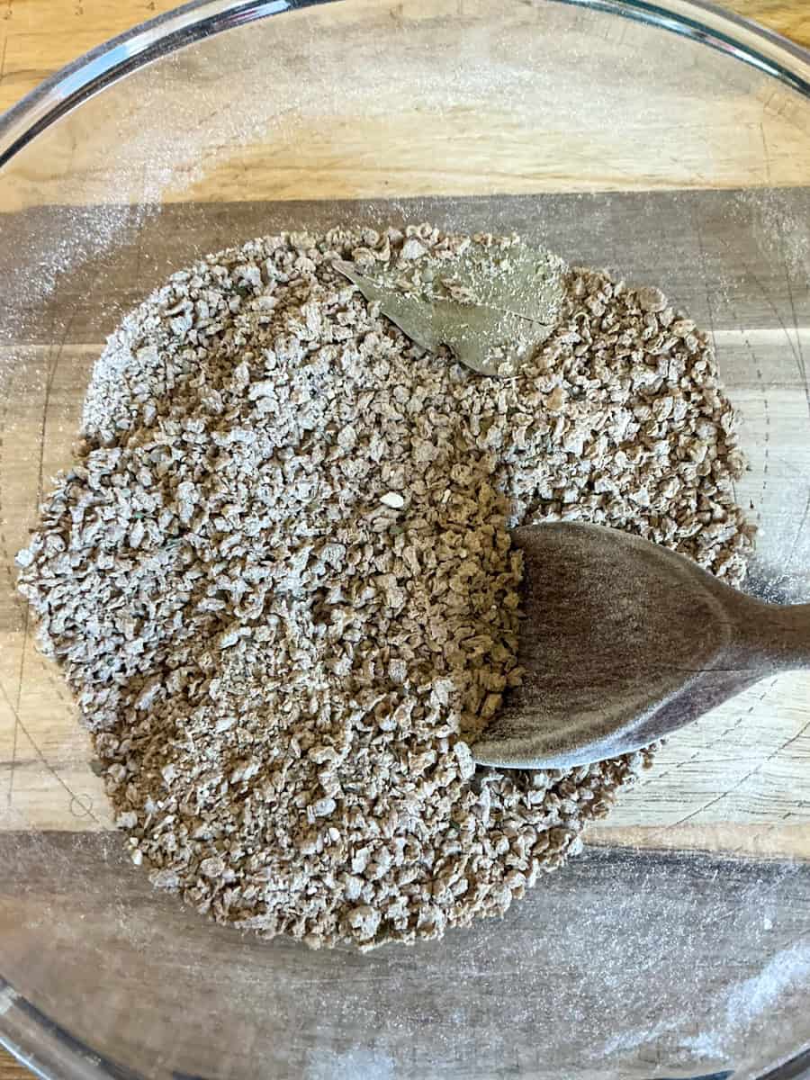 Beanfeast Bolognese dried mix ingredients stirred together in bowl.