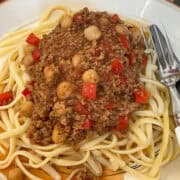 Homemade Beanfeast Bolognese served on plate with spaghetti and cutlery to side.