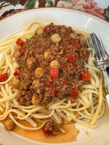 Homemade Beanfeast Bolognese served on plate with spaghetti and cutlery to side.