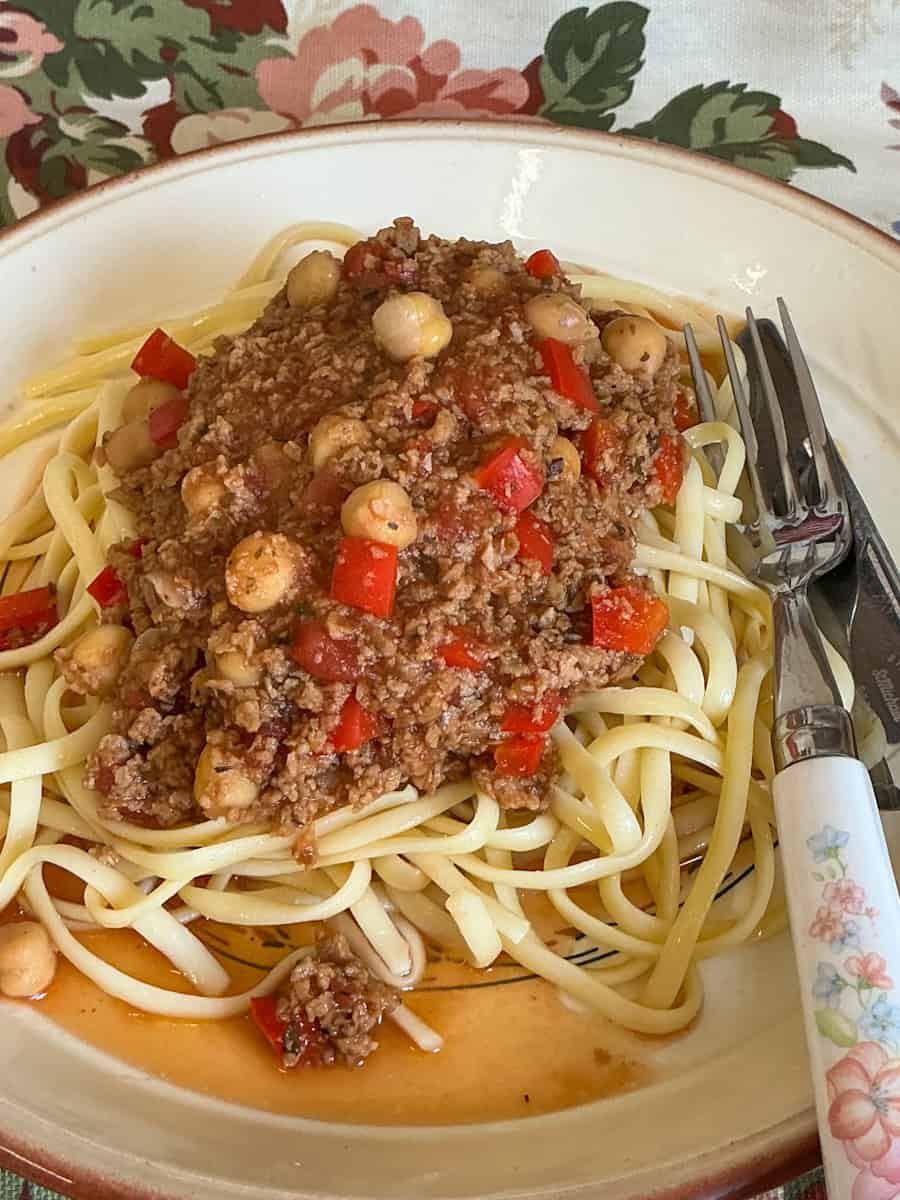 Beanfeast Bolognese served on dinner plate with cutlery to side.